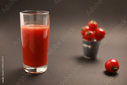 Close up view of tomato juice in glass and around cherry tomatoes isolated on black background with copy space 