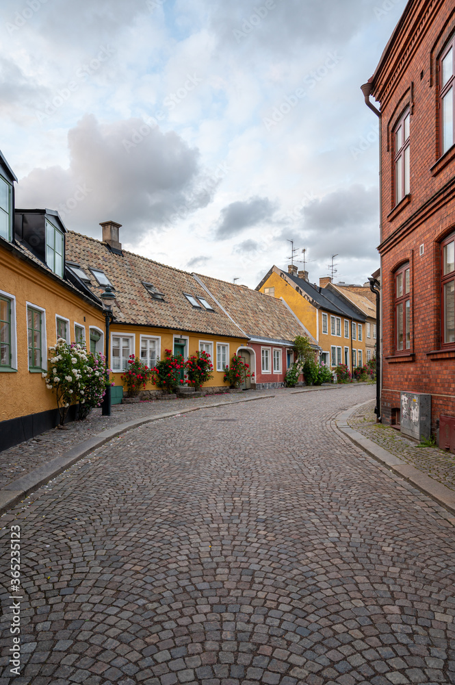 A cobblestoned street bordered with yellow and red townhouses in the historic old town of Lund, Sweden