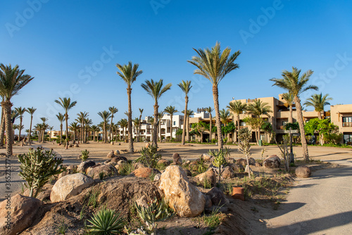 Luxury resort on the beach with palm trees ad stones. Oriental tropical hotel in Egypt