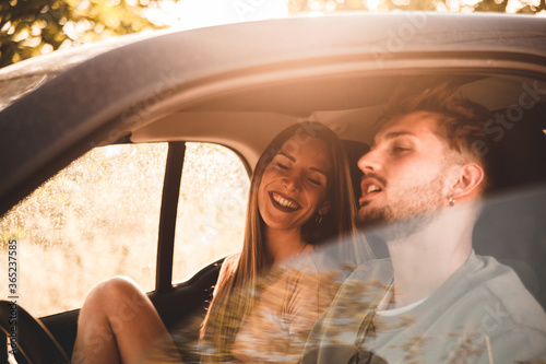 Young couple in the car smile lightheartedly during a relaxing moment of their holidays photo