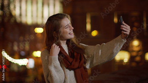 Girl showing victory sign cellphone camera. Happy woman taking selfie outdoor.