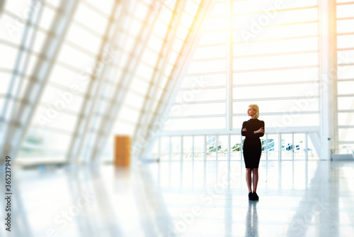 Young beautiful woman owner of successful model agency dressed in elegant black dress is standing in modern interior with copy space background for your advertising text message or promotional content