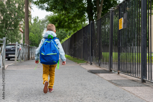 A little boy with blue bag is going to school. A child goes to primary school at first time. Back to school.