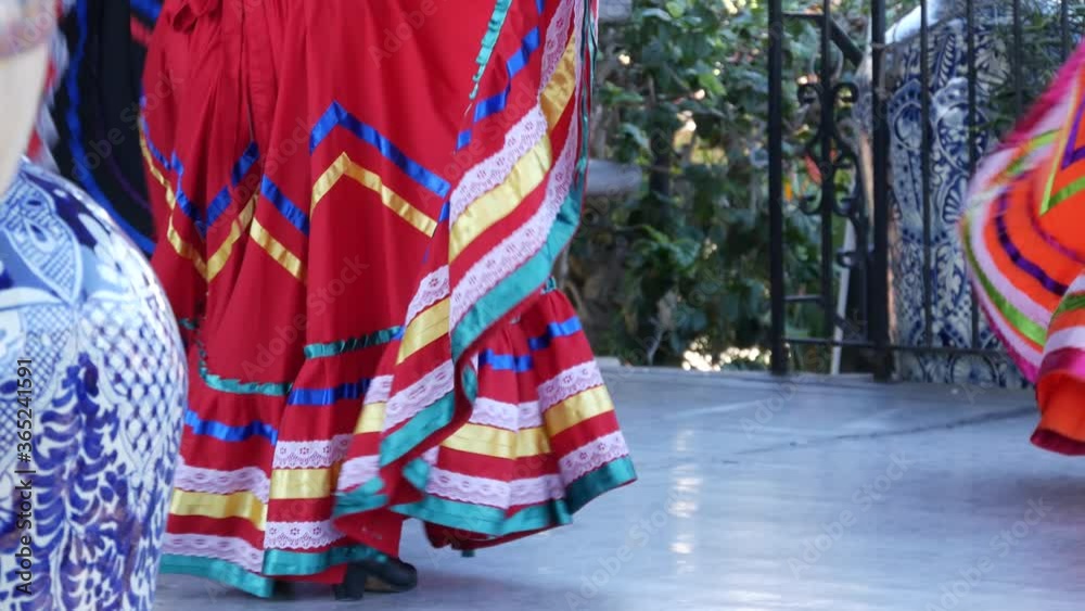 Latino women in colourful traditional dresses dancing Jarabe tapatio, mexican national folk hat dance. Street performance of female hispanic ballet in multi colored ethnic skirts. Girls in costumes.