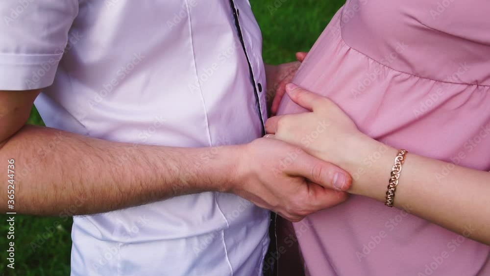 A man and a pregnant woman are holding hands in a park A man and a pregnant woman are holding hands in a park