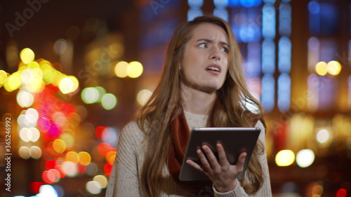 Upset woman using tablet outdoors. Confused girl looking tablet screen outside.