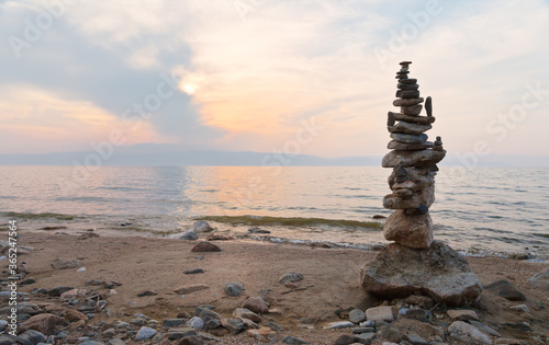 Baikal Lake at July evening. The big tourists stone pyramid on the beach of Olkhon Island at the background of sunset sky. Summer travel