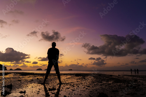 Silhouette of a man on the beach at sunset. Man rejoices meets the sunset