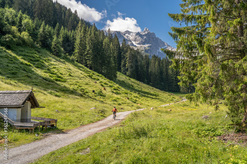 senior woman riding her electric mountain bike up to the Lindau Hut below the famous summits of Drusenfluh and Three towers in the Montafon Area of Vorarlberg Austria photo