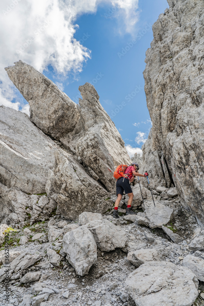 senior woman hiking in the wild terrain  below the Drosa Tor in the  mountains of Montafon valley, Vorarlberg, Austria