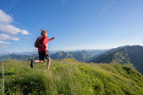 active senior woman mountain running in the early evening in warm dawn light on the ridge of the Nagelfluh chain in the Allgau Alps near Immenstadt, Bavaria, Germany