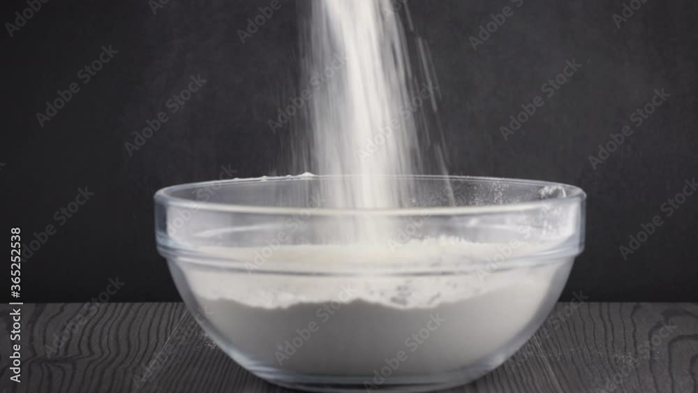 sprinkling flour in a transparent bowl close-up. cooking dessert at home sprinkling flour in a transparent bowl close-up. cooking dessert at home
