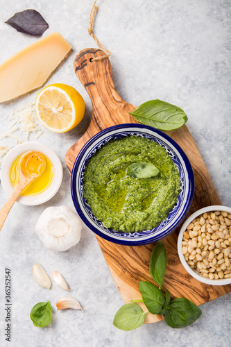 fresh Green basil pesto with italian recipe ingredients over light table copy space for text overhead