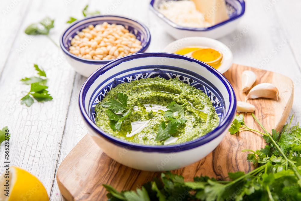 Homemade parsley pesto sauce and ingredients on white wooden background. Homemade parsley pesto sauce and ingredients on white wooden background.
