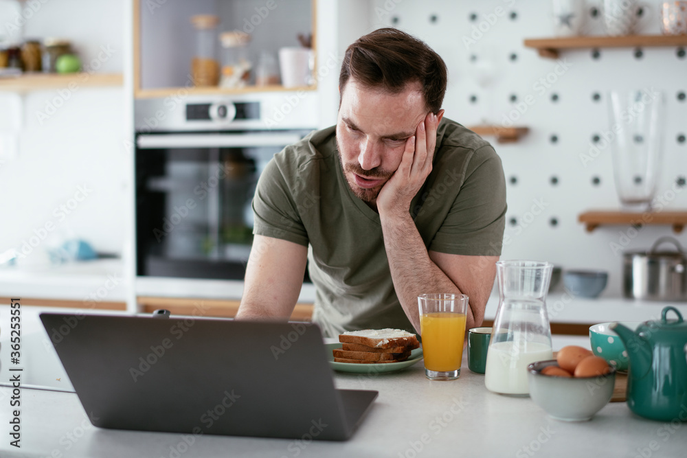 Handsome man preparing breakfast at home. Young man drinking coffee in kitchen.	