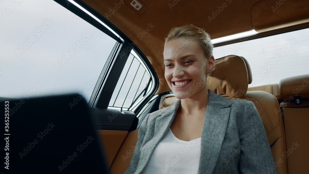 Successful businesswoman enjoying success in car. Business woman looking laptop