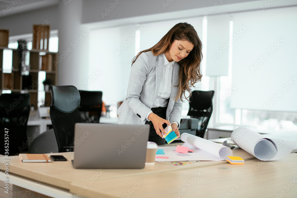 Beautiful young businesswoman working on project. Businesswoman in suit working in office.	