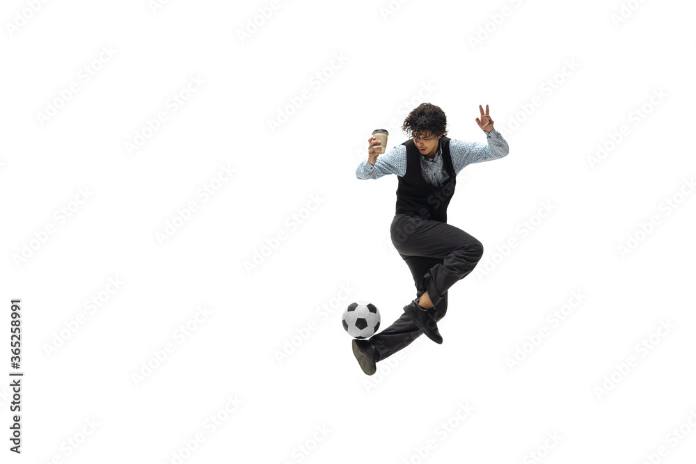 Man in office clothes playing football or soccer with ball on white background like professional player. Unusual look for businessman in jump kicking ball. Sport, healthy lifestyle, creativity.