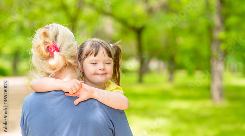 Woman holds in her arms a happy daughter with down syndrome. Empty space for text