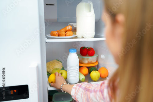 Hand of a woman taking food from the fridge