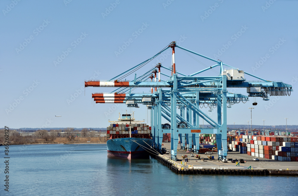 Newark, NJ / USA - View of the container terminal with berthed ship, gantry cranes are loading and discharging cargo from the vessel.