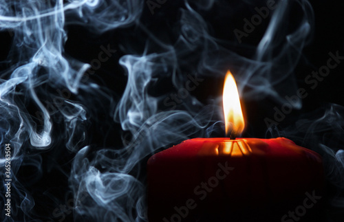 Red candle and smoke. Dark background.