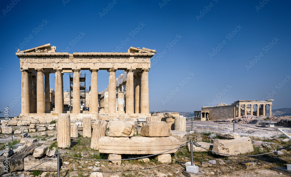 Panoramic view of the Parthenon and the Erechtheion of the Acropolis in Athens Greece shines in the warm sun before a blue sky and nobody is present.