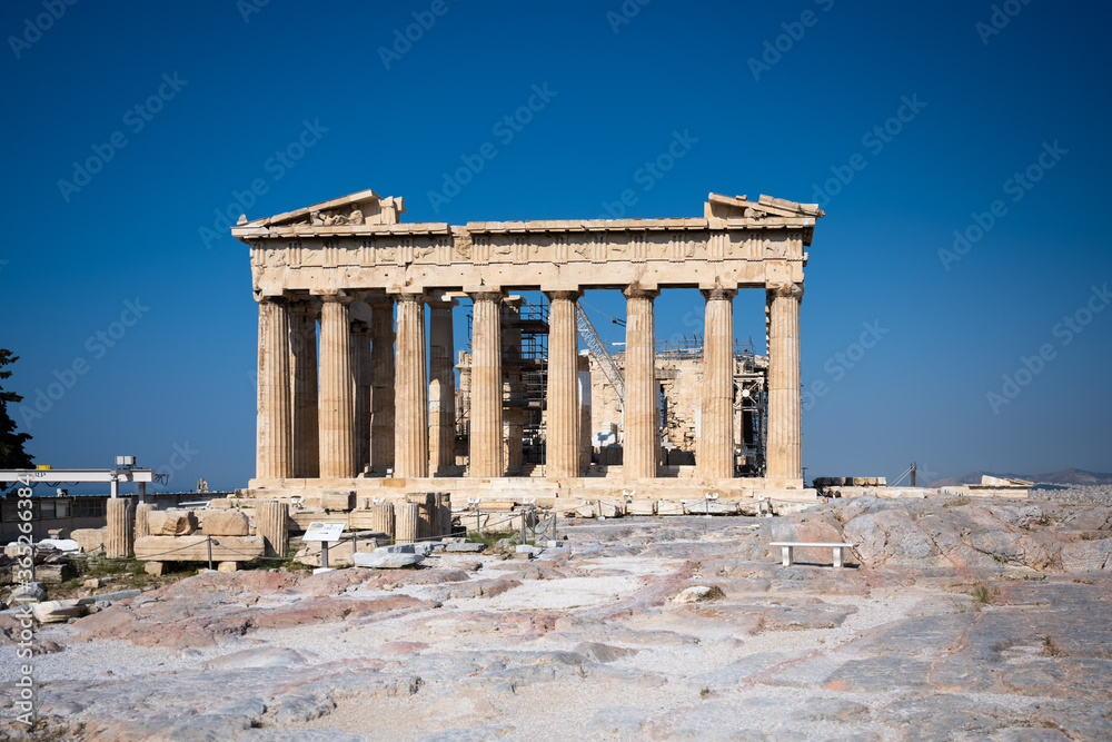 The Parthenon of the Acropolis in Athens Greece shines in the warm sun before a blue sky and nobody is present.