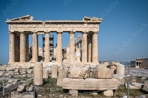 The Parthenon of the Acropolis in Athens Greece shines in the warm sun before a blue sky and no one is present.