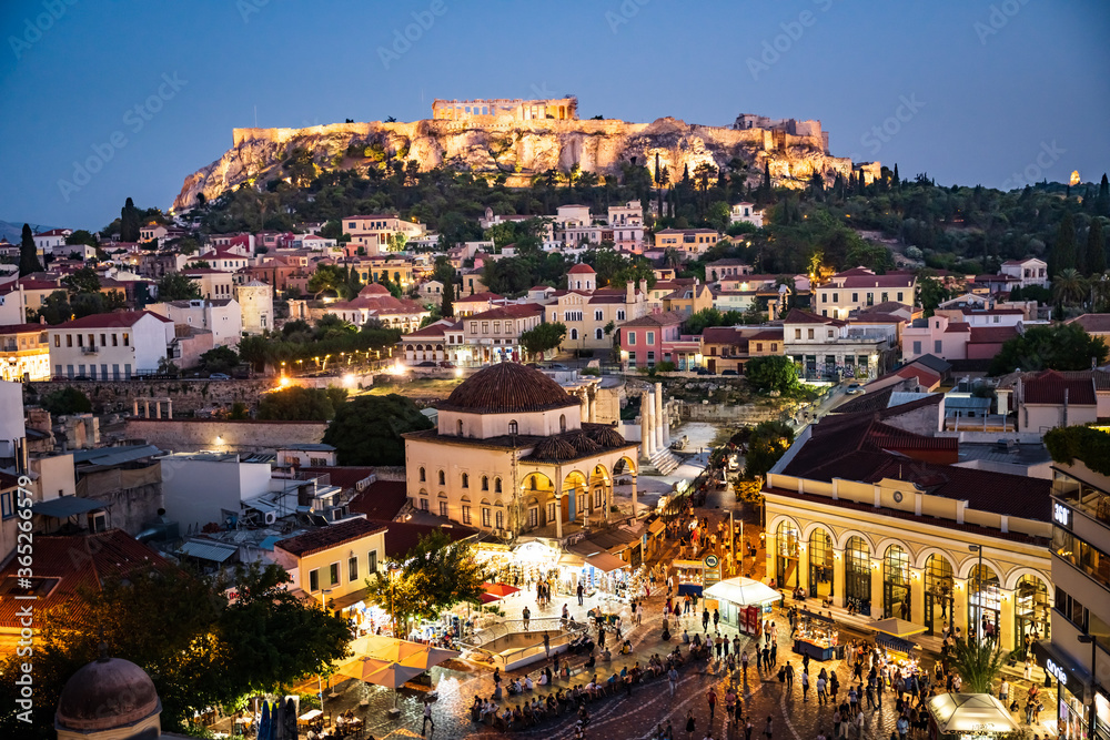 The historical Acropolis in Athens Greece is enthroned above the lively old town Plaka with scenic lighting at night.