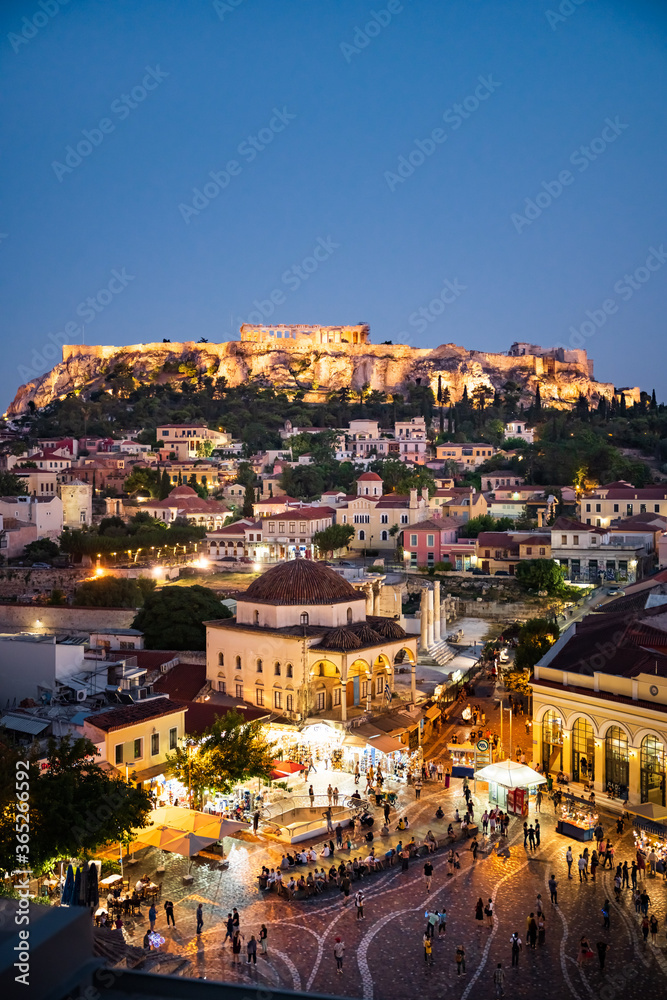 The historical Acropolis in Athens Greece is enthroned above the lively old town Plaka with scenic lighting at night.