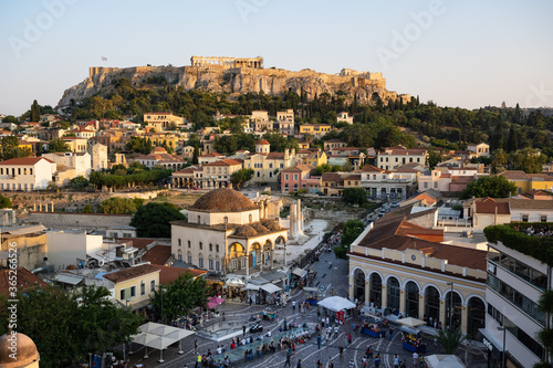 The historic Acropolis in Athens Greece is enthroned above the lively old town of Plaka in the evening light.