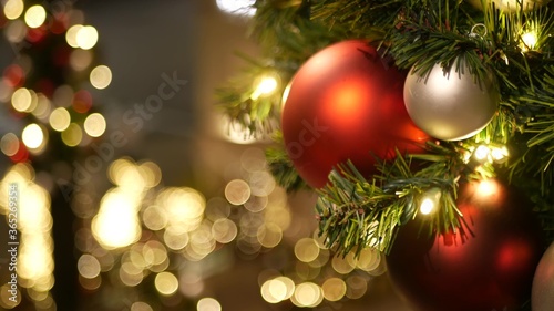 Closeup of Festively Decorated Outdoor Christmas tree with bright red balls on blurred sparkling fairy background. Defocused garland lights, Bokeh effect. Merry Christmas and Happy Holidays concept.
