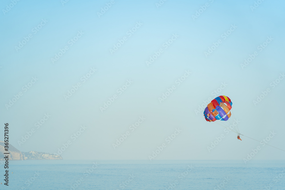 paragliding couple doing extreme sport in the middle of the ocean with beautiful blue sky paragliding couple doing extreme sport in the middle of the ocean with beautiful blue sky