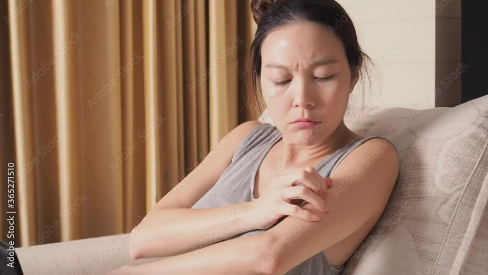 asian woman in living room using tablet got mosquito bite. female itchy and annoying, she try to hit mosquito. asian woman in living room using tablet got mosquito bite. female itchy and annoying, she try to hit mosquito.