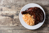 Traditional mole Poblano with rice in plate on wooden table. Top view. Copy space