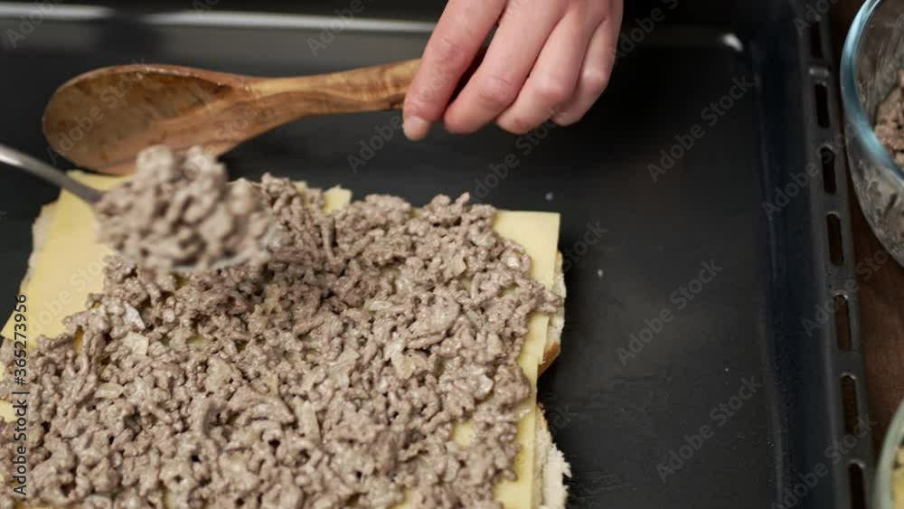 Adding fried ground beef on bread rolls in slow motion. Concept of