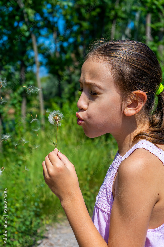 Pretty little girl picking a flower on a path surrounded by nature Pretty little girl picking a flower on a path surrounded by nature