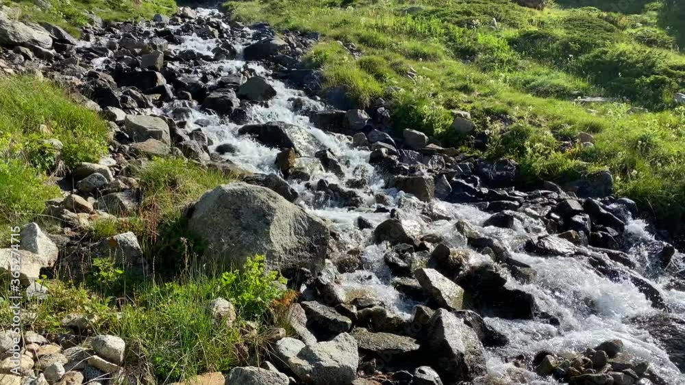 A beautiful mountain stream. Drinking water pours over stones. Natural source of clean water in the mountains. Alpine meadows. A beautiful mountain stream. Drinking water pours over stones. Natural source of clean water in the mountains. Alpine meadows.