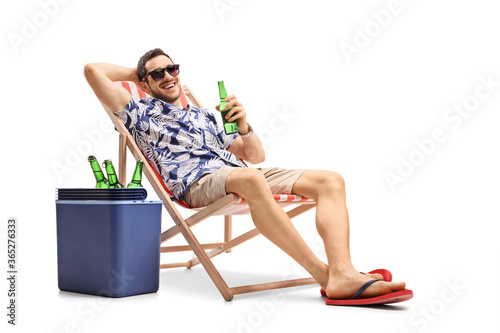 Canvas Print Tourist with a bottle of beer on a deckchair with a cooling box beside him