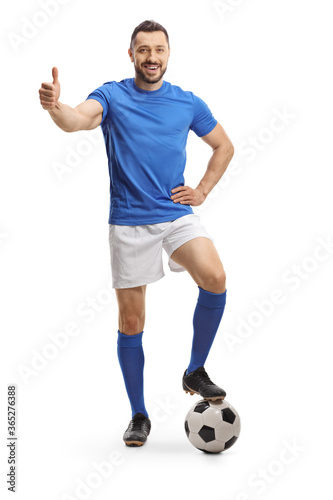 Soccer player in a blue jersey with his leg on a ball showing thumb up