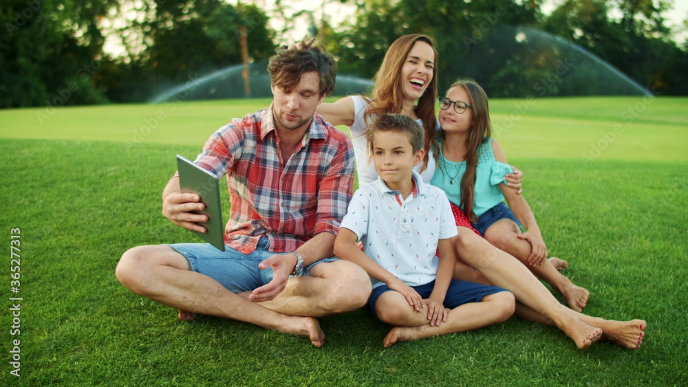 Family having conversation by video chat on pad in park. Family using tablet Family having conversation by video chat on pad in park. Family using tablet