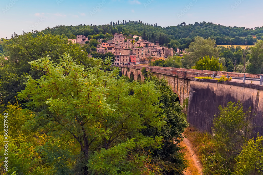 A view along the bridge over the River Tevere towards the village of  Pontecuti, Umbria, Italy in summer