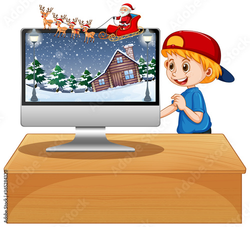 Boy next to computer on the table with xmas theme desktop background