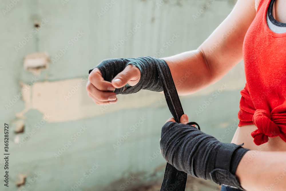 Close-up of fit, young woman putting boxing wraps, bandage on her hands.