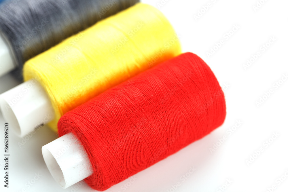 Sewing threads of different colors on reels on a white background. Free space, close-up. Isolate Sewing threads of different colors on reels on a white background. Free space, close-up. Isolate