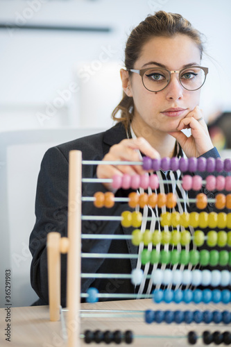 Segretaria bionda  annoiata fa i conti con il pallottoliere seduta nella sua postazione di lavoro del suo ufficio photo