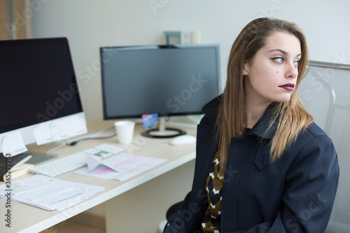 Manager bionda con gli occhi chiari che guarda seduta nella propria postazione