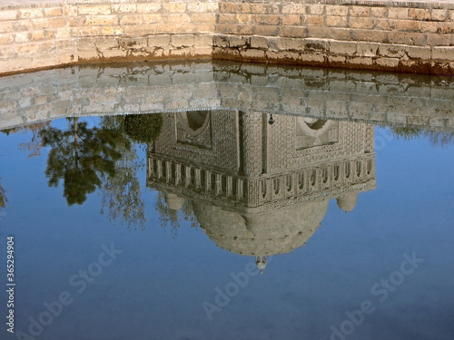 View on the ancient Samanid Mausoleum, reflecting in waters of howz (name of traditional pool). Building is made of baked bricks, it's a most old construction in Bukhara, Uzbekistan photo