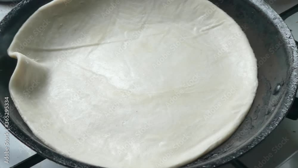 Indian Partha pancake placed in hot smoking stove pan to cook Indian Partha pancake placed in hot smoking stove pan to cook